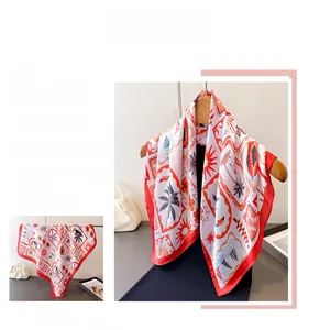 Detail of printed silk scarf with palm trees and sun motif hanging on a wooden hanger