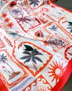 Detailed close-up of a tropical print silk scarf with toucan, palm trees and red borders