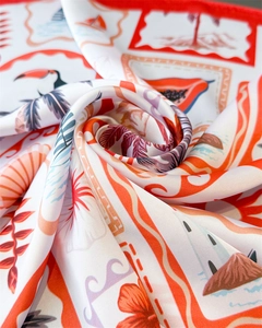 Macro shot of tropical print silk scarf with toucan pattern and vibrant red hem detail