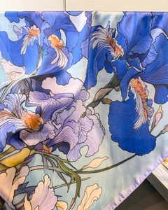 Detail of silk scarf showing vibrant iris flower print and delicate purple rolled hem edges