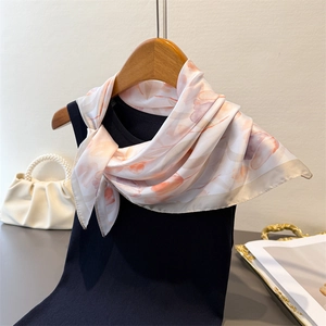 Detail of silk-like square scarf with tulip floral print hanging on a wooden hanger