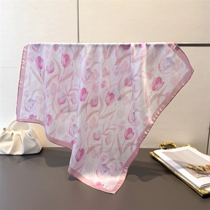 Close-up of elegant tulip print satin scarf with soft pink borders and a silky texture