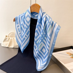 Detailed view of silk-like blue and white geometric scarf draped on a wooden hanger