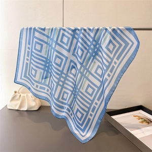 Elegant blue and white geometric printed silk scarf hanging in a minimalist setting