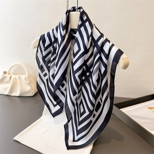 Classic black and white geometric pattern square silk scarf displayed on a white mannequin