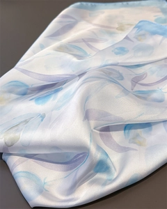 Detailed view of tulip print silk scarf with fine blue rolled edges and smooth texture