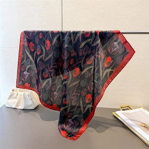 Detailed view of the red tulip pattern on a luxury black silk scarf draped over a stand
