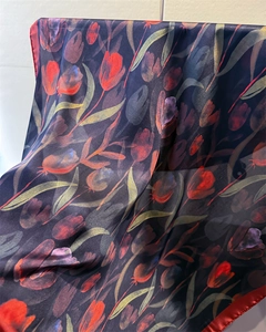 Close-up of semi-transparent silk scarf with red tulips and navy blue fabric texture