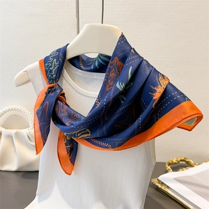 Detail of silk scarf with navy and orange tiger pattern styled on white knitwear