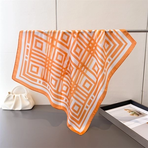 Detailed view of bright orange geometric pattern silk scarf with delicate hemmed edges