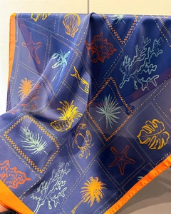 Close-up of tropical sea life print scarf showing silk texture and orange hem detailing
