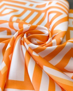 Close-up of geometric silk-like scarf featuring premium satin luster and orange-white pattern