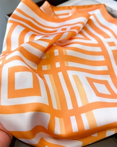 Close-up of bright orange and white geometric pattern on smooth satin silk scarf fabric