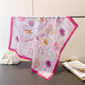 Close-up of tropical ocean print silk scarf with pink borders and palm tree patterns