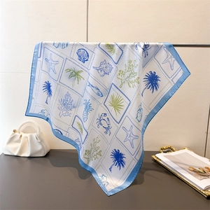 Detail of silk square scarf showing ocean print with palm trees and corals on a white base