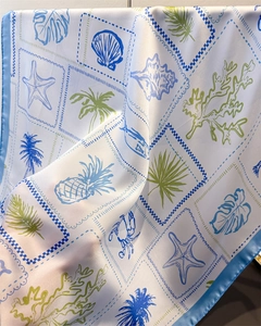 Detail of silk scarf showing vibrant ocean prints with seashells and palm leaves