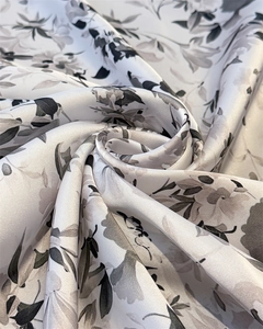 Dettaglio della texture liscia in raso e dell'elegante stampa floreale del foulard chic