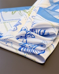 Detailed view of the ocean palm tree print scarf with smooth silk-like texture and blue hem
