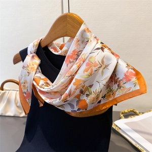 Elegante sciarpa di seta a fiori su una maglia nera con borsa bianca in un set di stile