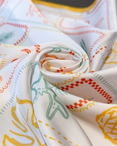 Detail of silk-like scarf featuring tropical coconut tree print and vibrant border patterns