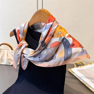 Detail of silk-like scarf with cartoon cat print draped on a black knitted vest