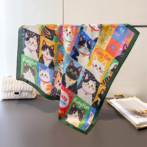 Detailed view of colorful silk-like scarf with cartoon cat prints on metal stand