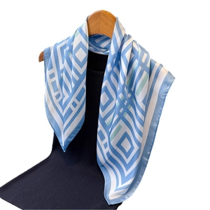 Sky blue and white geometric checkered silk scarf draped on a wooden hanger