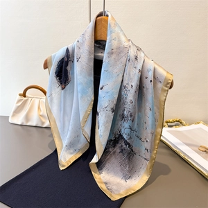 Ink painting silk scarf with blue abstract pattern and champagne gold hem on wooden rack