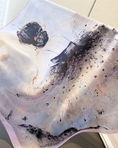 Detail of silk scarf showing translucent fabric with artistic ink painting of a woman