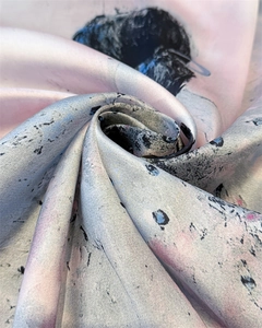 Detailed macro view showing the smooth satin texture and ink print of the silk scarf