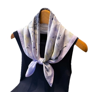 Ink-wash pattern silk scarf in purple and yellow tied on a black top against white background