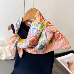 Detail of silk-like square scarf with tropical seashell print tied on a wooden hanger