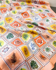Macro detail of silk-like scarf featuring tropical sea shell and palm tree print patterns