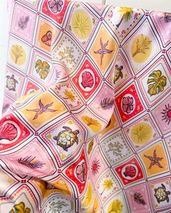 Detail of silk scarf with tropical ocean print featuring turtles and palm leaves
