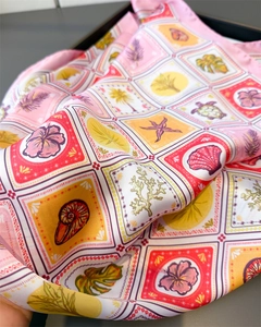 Detail of silk square scarf featuring tropical palm and seashell prints with soft folds