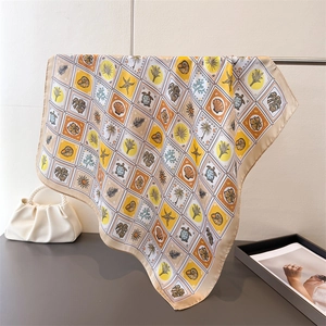 Close-up of square silk scarf with yellow tropical ocean pattern and satin finish