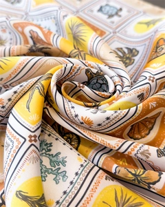 Detailed close-up of tropical ocean print silk scarf with turtles and palm leaves