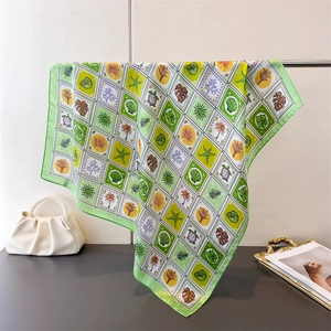 Detail of silk-like square scarf featuring tropical green grid patterns and leaf prints