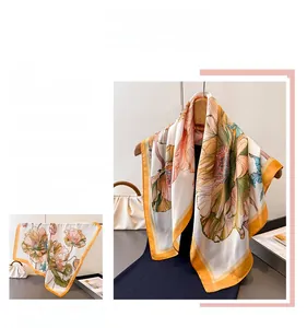 Detailed view of floral silk scarf with vibrant orange pink petals and yellow border