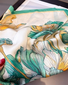 Detailed close-up of lotus print silk scarf with green rolled edges and floral patterns