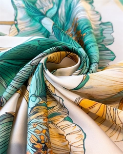 Detailed macro view showing the emerald and yellow floral silk scarf with soft fabric folds
