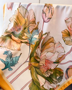 Detail of floral printed silk scarf showing warm orange petals and smooth texture drape