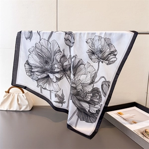 Detailed view of floral printed silk scarf with elegant black poppy flower patterns