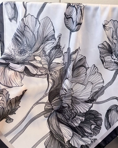 Detailed macro view of black and white floral print on glossy satin silk scarf fabric