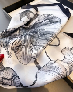 Close-up of black floral print on cream faux silk scarf with elegant rolled edges