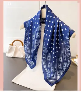 Détail du foulard en soie à pois bleus sur un cintre blanc avec un sac à main élégant