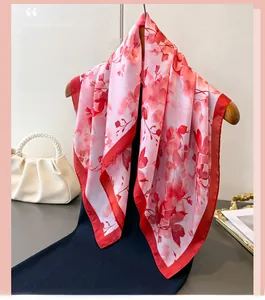 Détail d'un carré aspect soie à imprimé floral rouge sur un cintre en bois