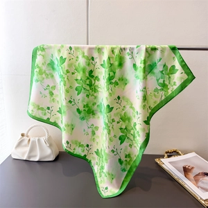 Détail de l'imprimé floral vert sur foulard carré en soie avec finition satinée