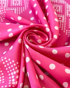 Détail d'un foulard en satin fuchsia à pois blancs montrant la texture soyeuse du tissu
