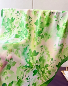 Gros plan d'un foulard en soie verte à fleurs montrant sa texture légère et transparente